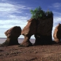 Colour photograph of tall red rock formations on a beach